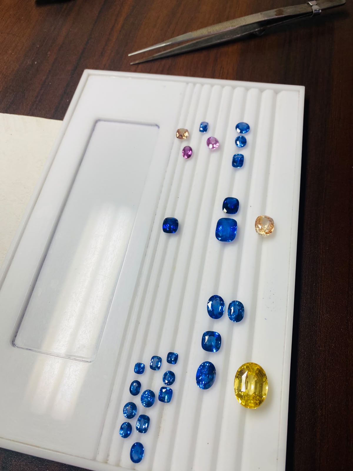 Supplied photograph of blue, pink and yellow loose gemstones on a tray